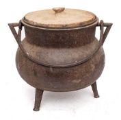 A bronze twin-handled cauldron: of bag shape with iron swing handle and tripod feet,