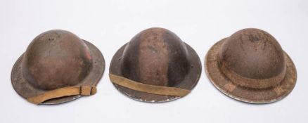 Three WWI Mk I pattern steel helmets, one with white band to skull,