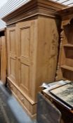 Pine two-door wardrobe with moulded cornice above two pebbled doors, above two drawers, on plinth