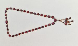 Victorian gold-coloured metal and garnet necklace with pendant drop, the oval graduated stones