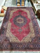 Persian-style carpet having shaped oval floral central medallion to the maroon ground, cream