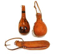 Three African gourd water pots, one featuring a painted savannah scene, the other decorated with dot