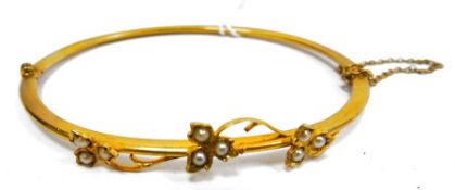Gold-coloured metal and seedpearl bangle, hinged and set with three trios of seedpearls in leafy