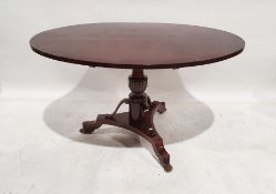 Unusual Regency loo table, the oval mahogany top on turned and carved pedestal, to a triform base,