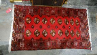 Iranian balouch rug, the red ground field with 16 elephant foot guls and decorative border, 168cm