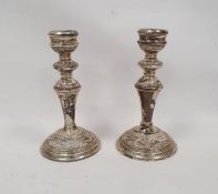Pair of 1920's silver weighted candlesticks, relief decorated on a circular base, Birmingham 1924,