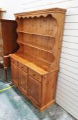 Pine dresser with moulded cornice above two shelves, on curved rectangular base with three drawers