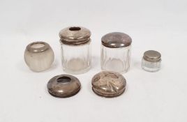 Two silver lidded glass jars, a silver-mounted candlestick holder, two loose silver lids and a