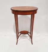 Edwardian flame mahogany oval two-tier occasional table with ebonised strung sabre legs