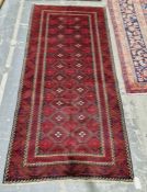 North East Persian Meshed Belouch red ground rug with two rows of eleven lozenge medallions enclosed