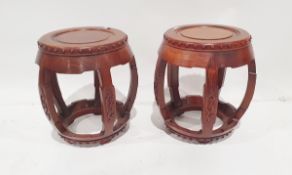 Pair Oriental hardwood barrel-shaped stools, each with four scroll carved curved supports, tab