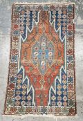 Eastern style red ground rug with central geometric medallion enclosed by floral pattern to a