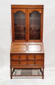 Oak bureau bookcase with glazed double doors above panelled fall front, revealing two drawers and