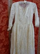 A 1950's figured satin wedding dress, some staining and damage to the train with an embroidered,