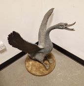 Bronzed finish modern garden cast model of a swan with wings displayed, on circular base, 79cm