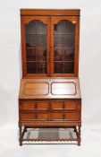 Oak bureau bookcase with glazed double doors above panelled fall front, revealing two drawers and