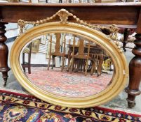 Gilt oval wall mirror with bevelled edge, 86cm wide