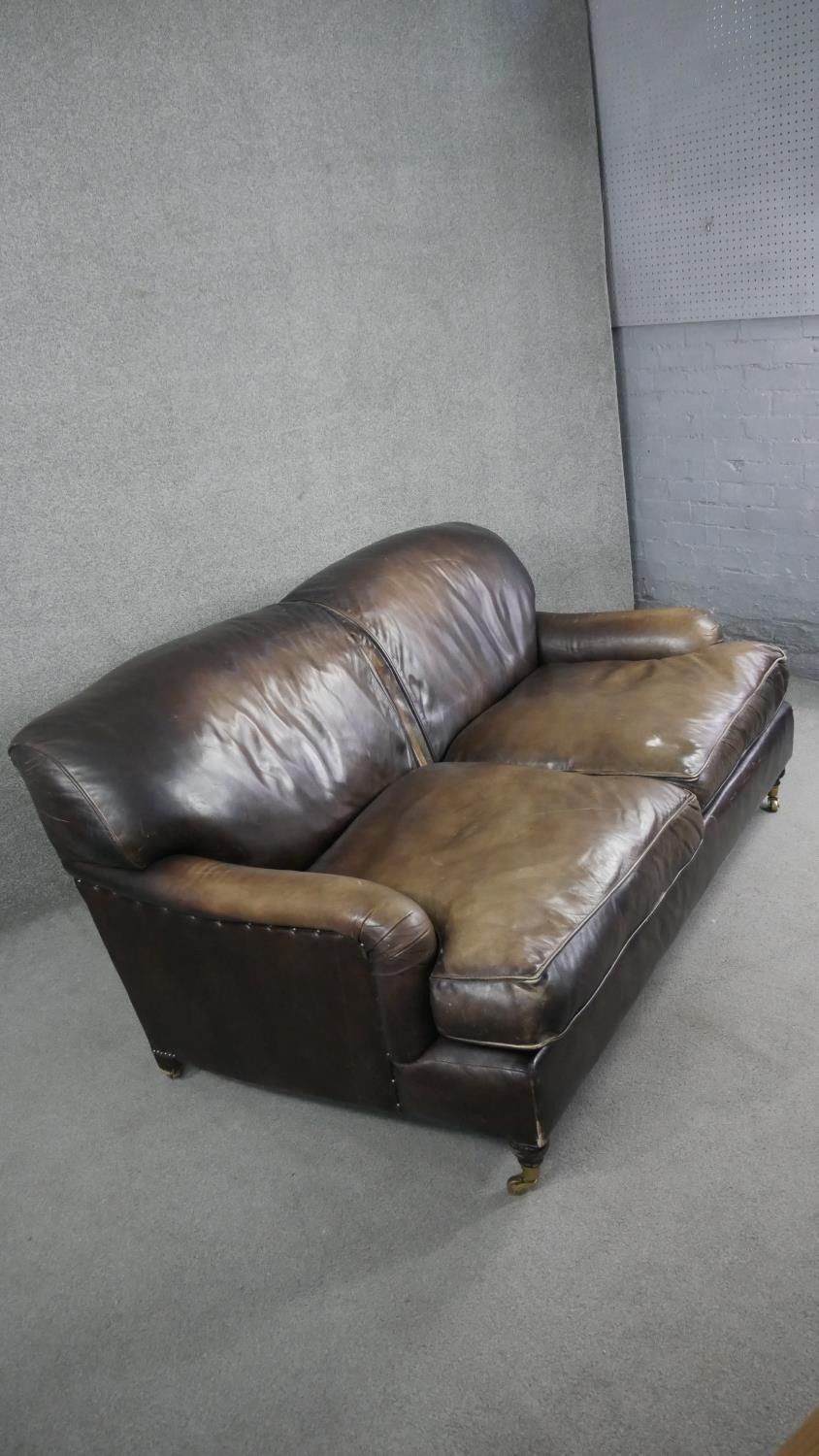 A Howard style two seater sofa in leather upholstery on turned supports terminating in brass - Image 2 of 7