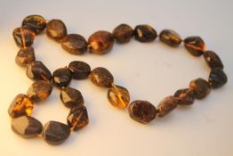 A large knotted statement necklace of a string of twenty seven polished amber beads. Weight. 101g.