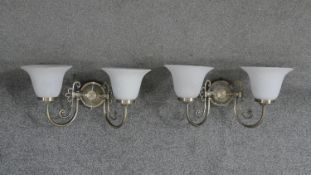 A pair of brushed brass and glass two branch wall lights. Each with two bell shaped frosted milk