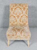 A vintage nursing chair in cut floral fabric on splay supports.