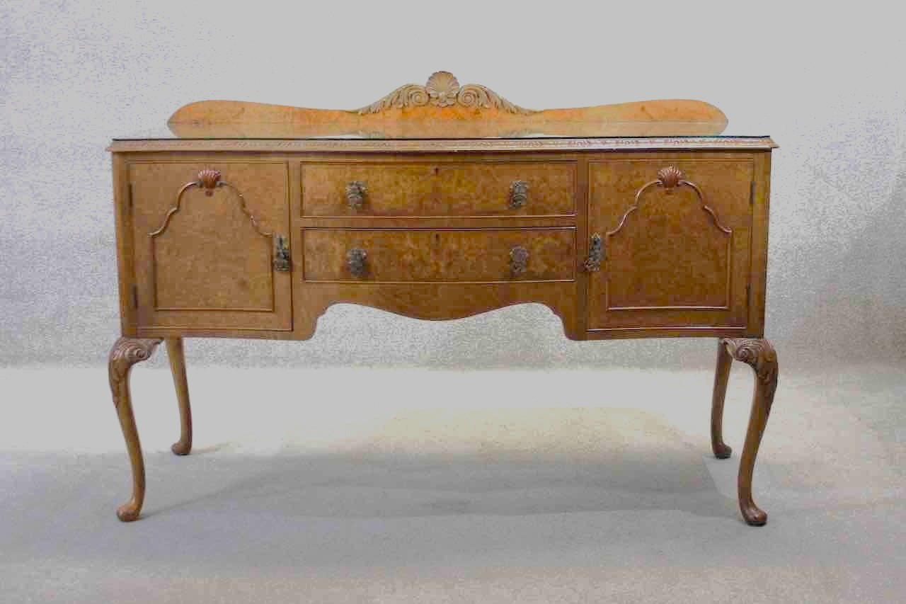 A mid century burr walnut Epstein sideboard with central drawers flanked by cupboards on carved