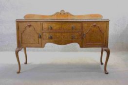 A mid century burr walnut Epstein sideboard with central drawers flanked by cupboards on carved