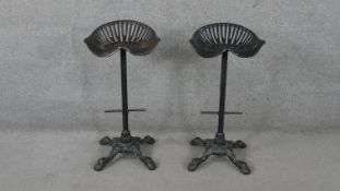 A pair of vintage cast iron tractor seat high stools on quadruped foliate supports.