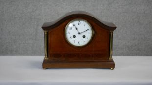 An Edwardian mahogany and satinwood inlaid mantel clock with white enamel dial flanked by brass