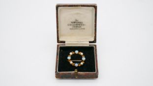 A 9 carat yellow gold opal and cultured pearl wreath brooch. The brooch is set with four round