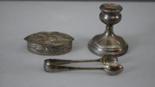 A collection of silver. Including a weighted silver candlestick, a pair of silver sugar tongs and