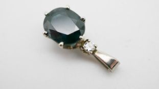 A white metal (tested platinum) sapphire and diamond pedant. Set with an oval mixed cut sapphire