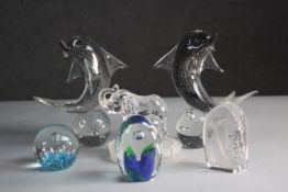 A collection of six art glass paper weights. A pair of dolphins balancing on balls, mum and baby