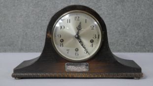 A vintage oak cased mantle clock with silver inscribed presentation plaque. Silvered dial and