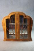 An Art Deco walnut cloud shaped display cabinet with sunray astragal glazed doors on plinth base.