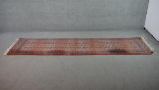 An orange ground Bokhara motif runner. L.281 W.69cm