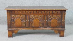 A 17th century style oak coffer, the carved front with faux panels, the feet with shaped brackets.