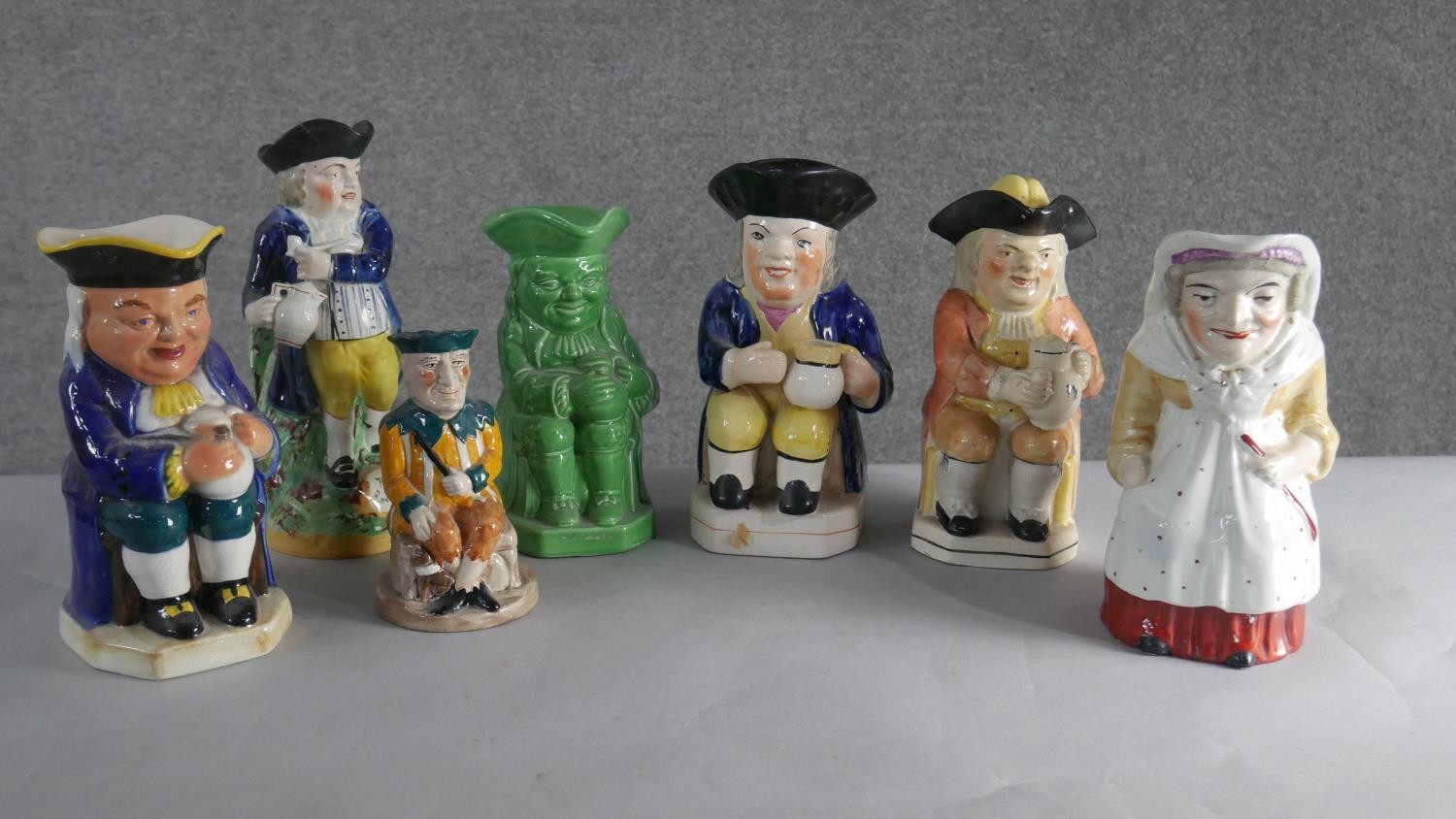A collection of seven hand painted early 20th century ceramic Toby jugs of various designs. H.28 W.