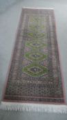A green ground Bokhara motif runner. L.207 W.136cm