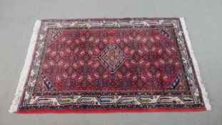A red ground Persian handmade Hamadan rug. L.145 W.112cm