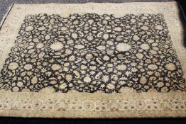 An Indian sari silk carpet with scrolling foliate decoration across the field within floral multiple