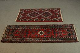 A small Persian rug on burgundy ground and a similar rug. L.143 W.49cm.