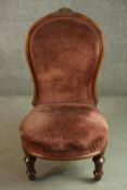 A Victorian walnut nursing chair, upholstered in velour, on turned and fluted legs.