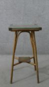 A gold painted Lloyd loom wicker jardiniere stand, with a square glass top, the legs joined by an