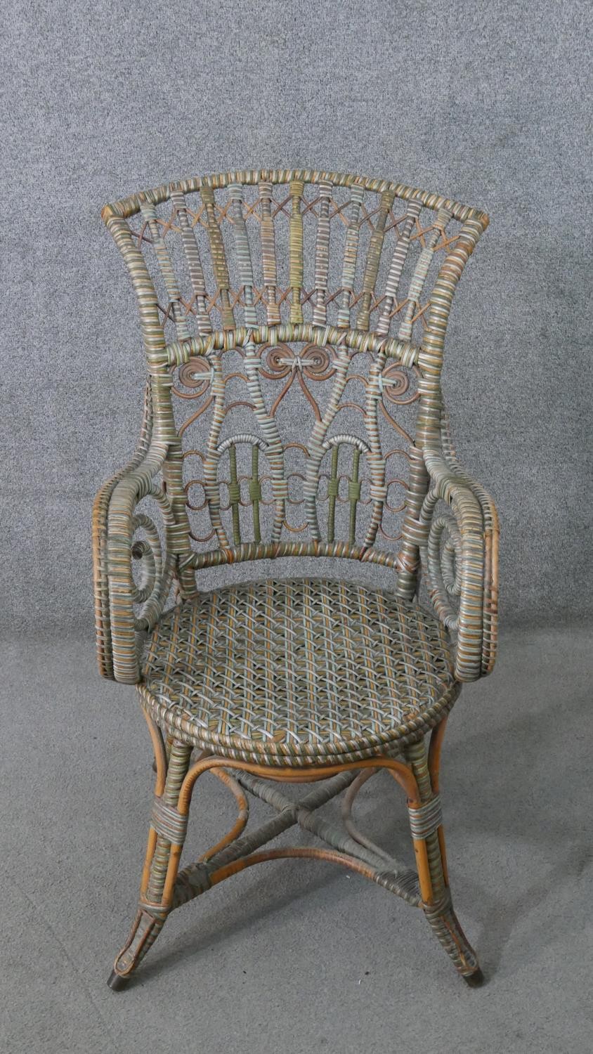 A wicker open arm conservatory chair, the back with cross and spiral detail, the arms with scrolling