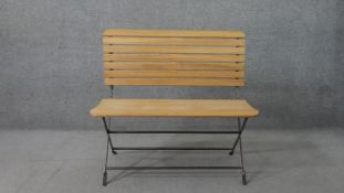 A contemporary folding garden bench, with a slatted seat and back, on a black painted iron frame.