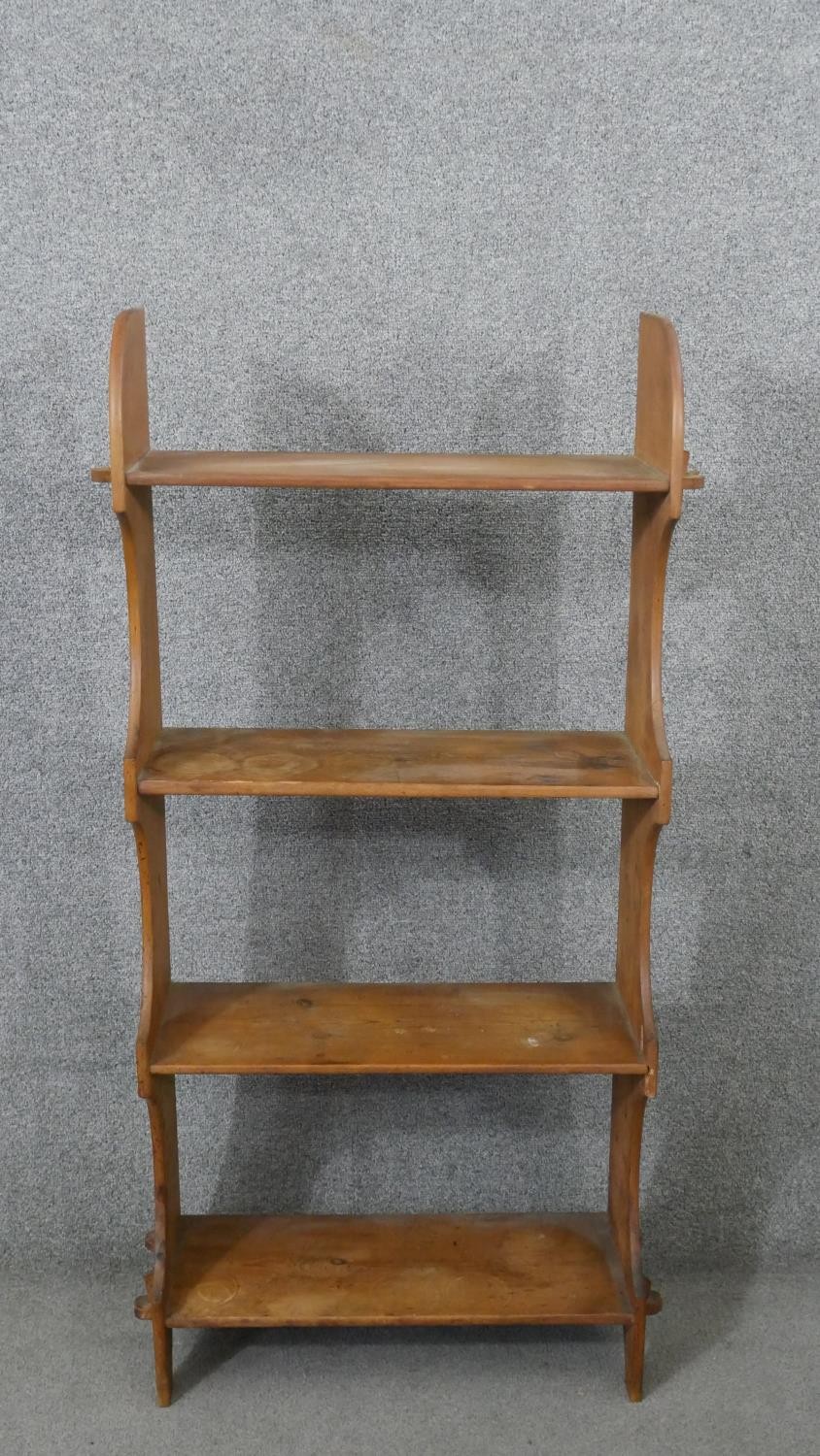 A set of pine open bookshelves, the four shelves joined to the shaped side with pegs. H.121 W.60 D.