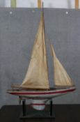 An early to mid 20th century pond yacht, in need of repair, with two sails, the wooden hull