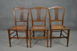 A set of three Edwardian mahogany and line inlaid dining chairs, with a pierced back splat, over a