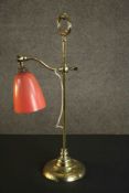An Edwardian brass adjustable desk lamp with orange bell shaped shade. H.58 W.23cm.